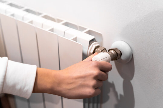 Girl feeling cold with home heating trouble. Energy crisis concept. Radiator thermostat showing cold temperature. Electricity and gas bill goes up. Radiators turns off. Heating problem. Degress