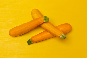Three yellow zucchini on yellow background.