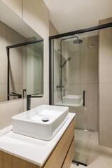 Interior of modern style bathroom in refurbished apartment. Shower zone and sink with black faucet and mirror.