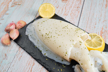 Cuttlefish sepia on dark stone plate with lemon and garlic copy space wood background fresh and healthy sea food