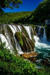 Fototapeta na wymiar Vertical of the beautiful Strbacki buk waterfall in Bosnia and Herzegovina with foamy water