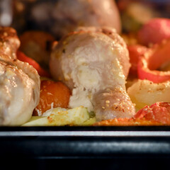 Cooking chicken with vegetables in the oven. Chicken legs and thighs with marinade, potatoes, tomatoes and paprika