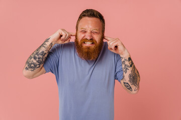 Ginger white man with beard grimacing and plugging his ears - obrazy, fototapety, plakaty