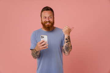 Ginger white man using cellphone and pointing finger aside