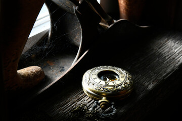 An old vintage pocket watch resting on a window ledge with dramatic lighting. 