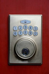 A close up image of an electronic keypad entry system on a bright red door. 