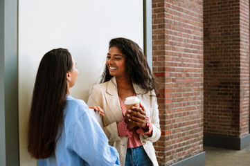 Two multinational women talking while standing by building outdoors