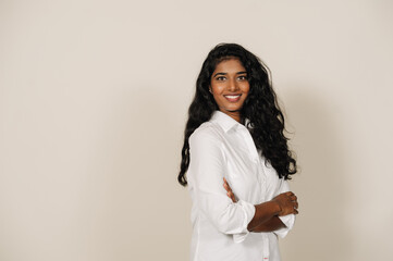 Young indian woman smiling at camera and standing with arms folded