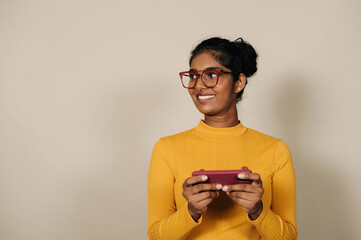 Young brunette indian woman smiling and using cellphone