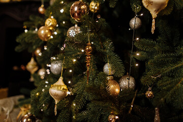 Close up view of beautiful fir branches with shiny golden bauble or ball, xmas ornaments and lights, Christmas holidays background. copy space. Decoration on christmas tree. Festive new 2023 year