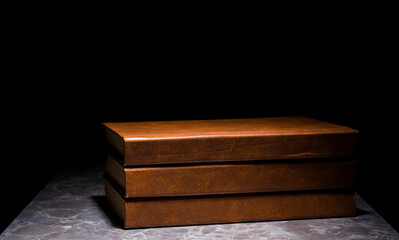several books with the same binding on a dark background isolated. three books with a brown cover without inscriptions and titles with free space for text