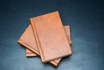 several books with the same binding on a dark background isolated. three books with a brown cover...