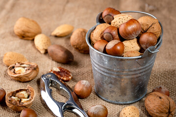 Assorted various nuts in a metal bucket on burlap. close-up.