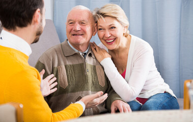 Elderly father and his daughter warmly and friendly conversation with her son at home