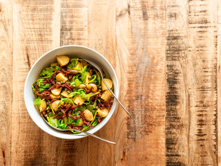 salad with dry tomatoes and potatoes on wooden table