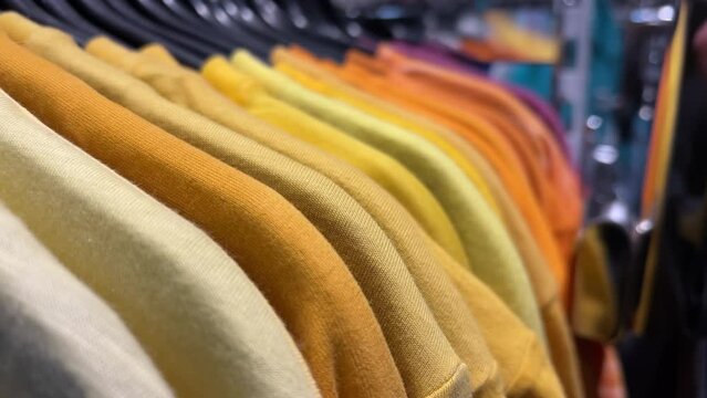 Multicolor sweatshirts hang on hangers in a clothing store. Closeup shot