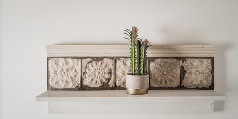 Artificial cactus home deco interior with flowers in a vase on the wall shelf