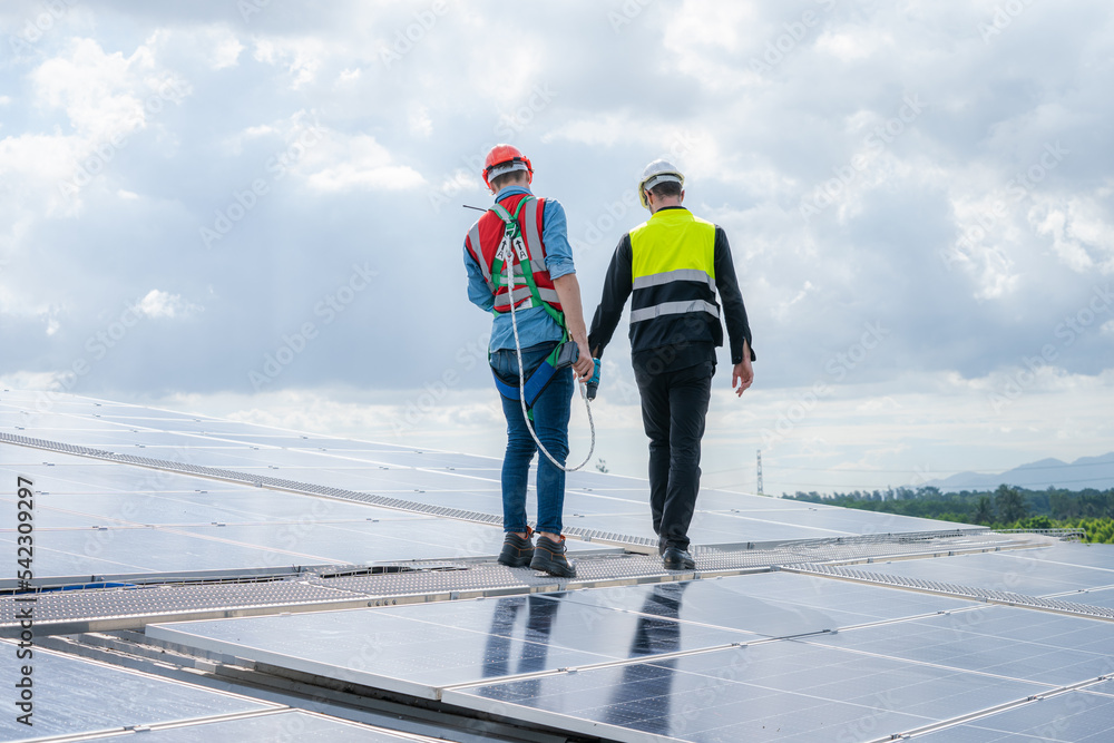 Poster engineers checking the operation of the system solar cell on roof at factory,alternative energy to c