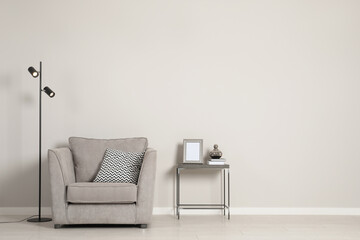 Stylish armchair near grey wall, space for text. Interior design
