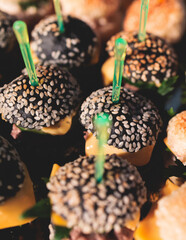 Burger mini burgers snacks on a wooden table with craft paper, beautifully decorated catering banquet table on a corporate christmas birthday party event or wedding celebration