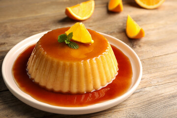Delicious pudding with caramel, orange and mint on wooden table - obrazy, fototapety, plakaty