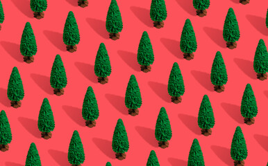 Minimal composition pattern background of green Christmas trees on pastel red. New Year concept.