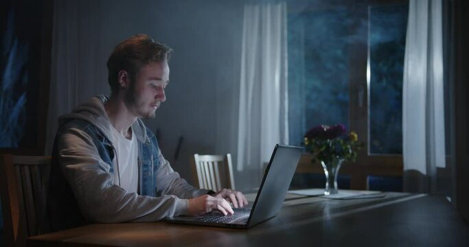 someone is typing on the laptop in the living room at night with fog and light from outside (film set)