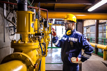 Power plant worker standing by gas pipes and controlling electricity production during energy...