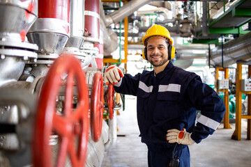 Portrait of factory worker standing by pressure pumps inside heating energy plant.
