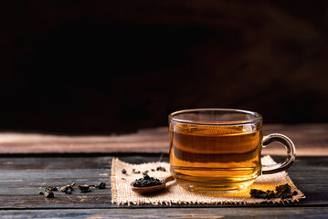 Hot tea in cup glass with dried tea leaves on wooden background, Healthy drink