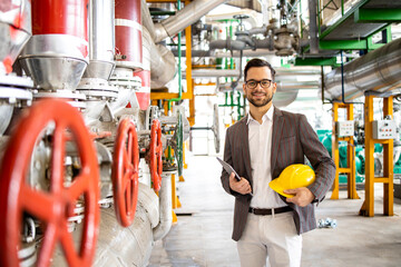 Portrait of an elegant factory manager standing inside boiler room of the heating plant.