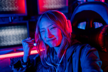 Winning or You Win. Young woman gamer champion excited, Happy gamer people playing video game online with smart mobile phone with neon lights raises hands to wins celebrating, game and e-sports.