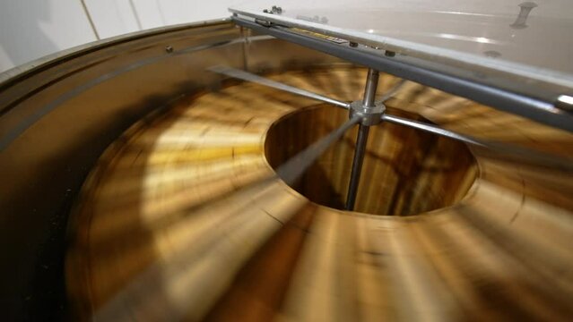 Getting the fresh healthy organic honey from the honeycombs. Switched on electric honey extracting machine with open lid close up.