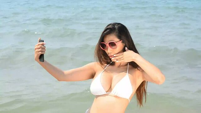 Pretty Asian woman taking a selfie on the beach.