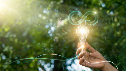 Circular economy. Hand hold light bulb with circular icon. Energy consumption and CO2 emissions,...