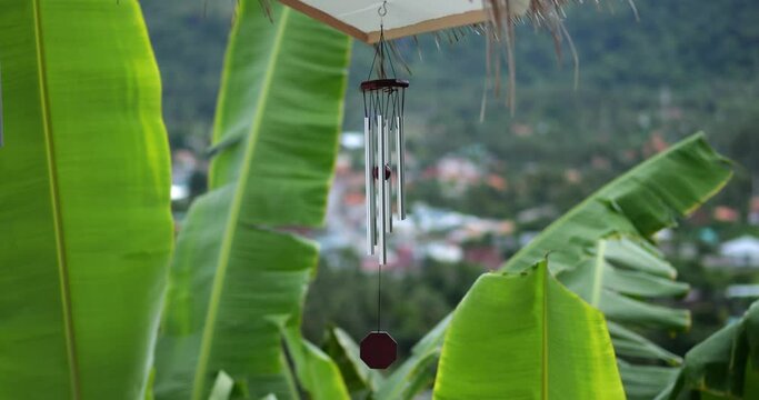 Wind Chimes hangs on the porch of the house against the backdrop of the tropical jungle and mountains