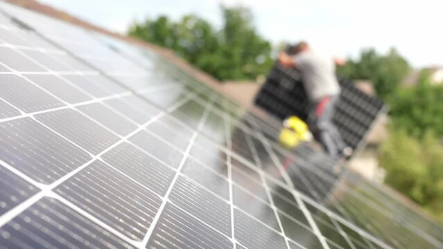 Technician carry solar panel cells to install on roof, static blurring