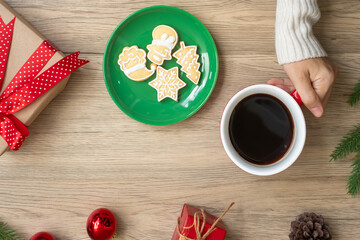 Merry Christmas with woman hand holding coffee cup and homemade cookie on table. Xmas eve, party, holiday and happy New Year concept