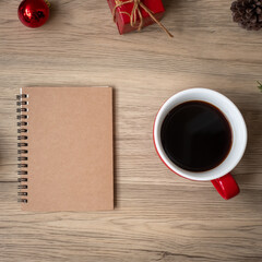 Blank notebook, black coffee cup and Christmas gift on wood table, Top view and copy space. Xmas, Happy New Year, Goals, Resolution, To do list, Strategy and Plan concept
