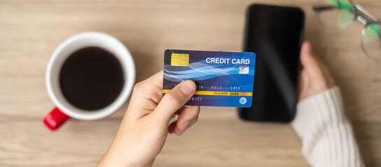 Hand holding credit card for online shopping on smartphone during drinking coffee. Merry Christmas eve, December, seasonal, Black Friday sale, New Year and holiday concept