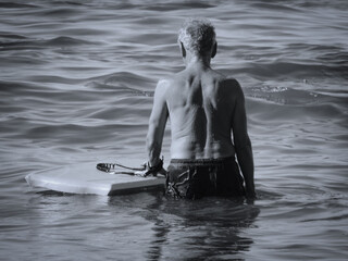 old man / retired man at the sea, holding a boogie board,  black and white photo