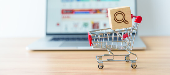 Shopping cart with Magnifying icon block and laptop computer with marketplace website, technology,...