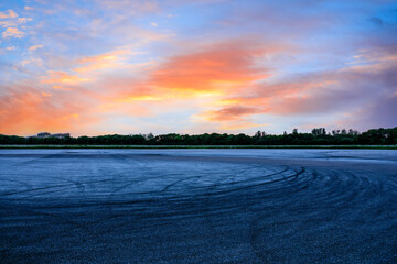 Empty asphalt race track road and green forest with sky clouds at sunset © ABCDstock