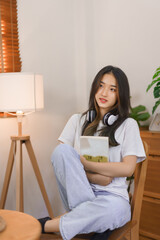 Relax at home concept, LGBT lesbian female sits on chair and hugging book while thinking something