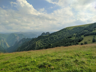 Naklejka premium Beautiful view of the Caucasus Mountains and green hills covered with trees against a sky with clouds. Prielbrusye National Park, Kabardino-Balkaria, Caucasus, Russia