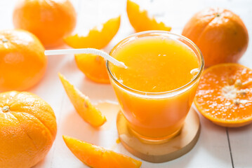 Fresh orange juice in the glass with orange fruit on white wood
