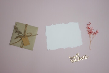 Letter concept with white paper, brown envelope and flowers on pink background. 