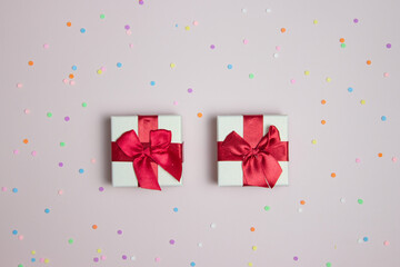 Gift boxes with colorful confetti over the pink background. 