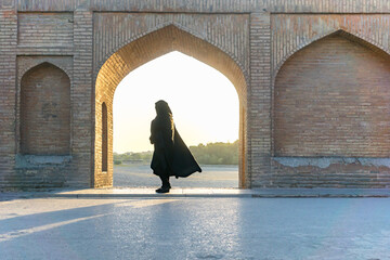 Islamische Frau mit traditionellem Kopftuch und Kleid auf der Khaju-Brücke in Isfahan, Iran. nicht identifizierbare Silhouette wie die Form einer iranischen Frau in islamischem Stoff