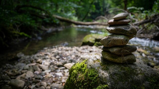Closeup of stacked rocks in background of flowing river